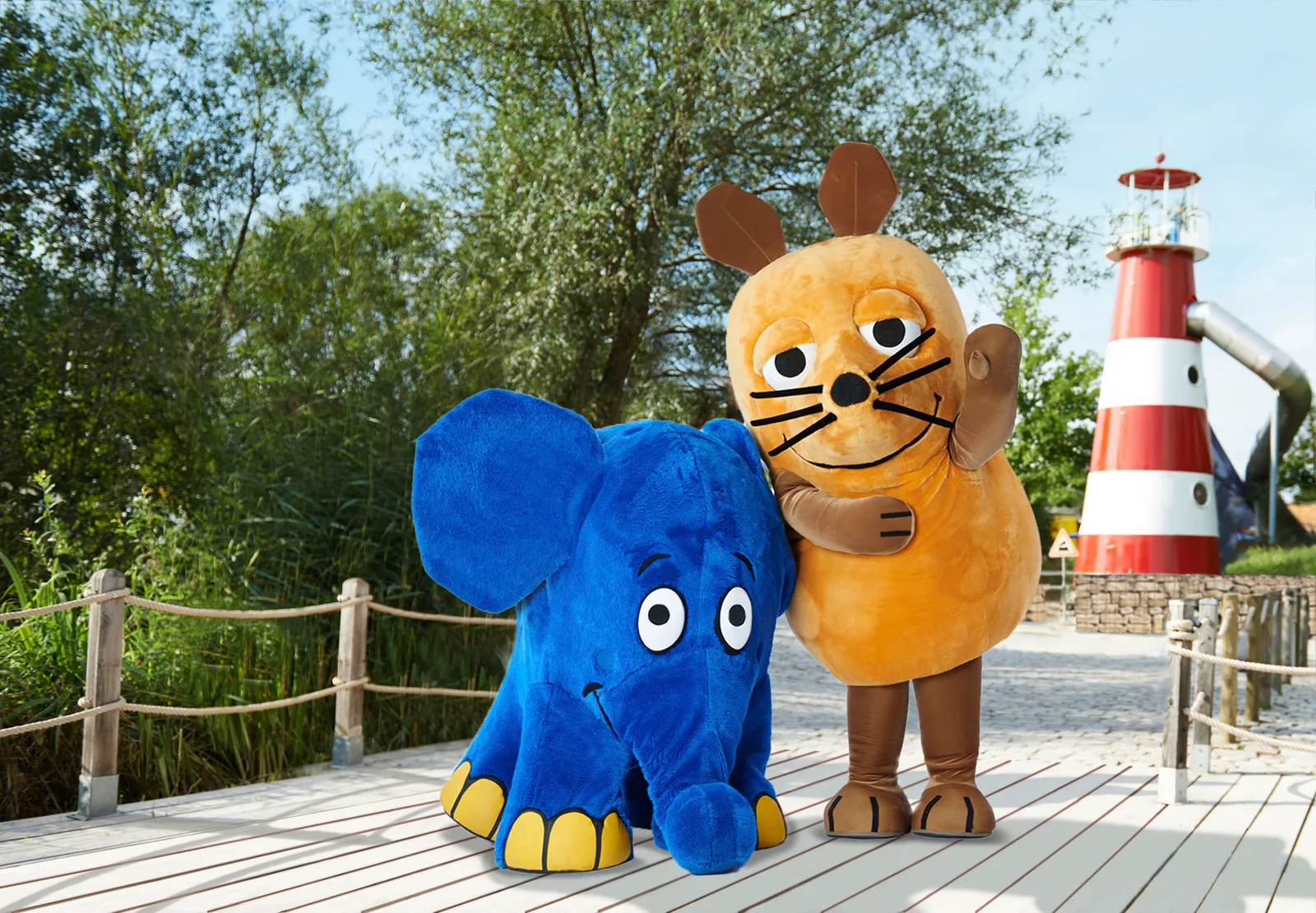Mouse and Elephant at Ravensburger Spieleland in front of the red-and-white lighthouse